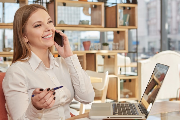 Charming business woman talking on the phone at coffee shop