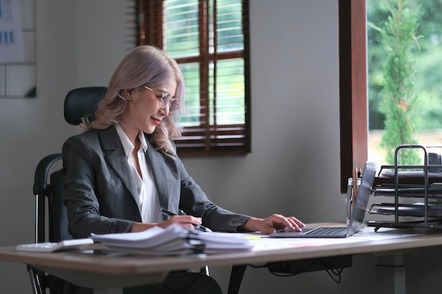 Charming businesswoman working on laptop at her workplace at modern office