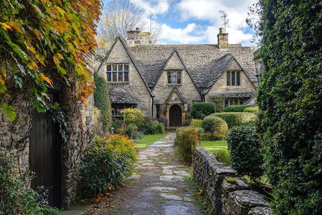 A Charming Cotswold Cottage Stone walls lush greenery and a stone pathway lead to a picturesque home in the English countryside