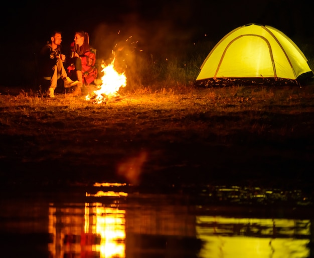 Charming couple, camping, sitting around the campfire