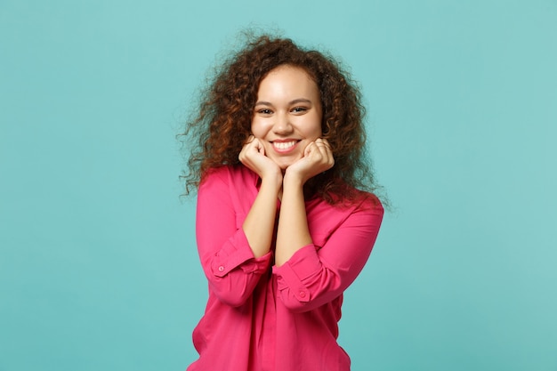 Charming cute african girl in casual clothes looking camera, put hand prop up on chin isolated on blue turquoise background in studio. People sincere emotions, lifestyle concept. Mock up copy space.