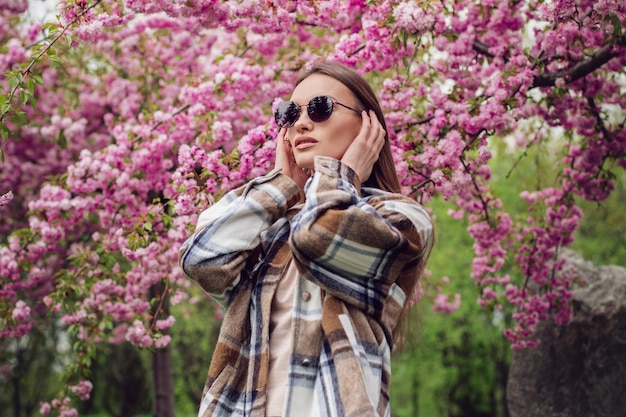 Charming fashionable woman in blooming sakura park