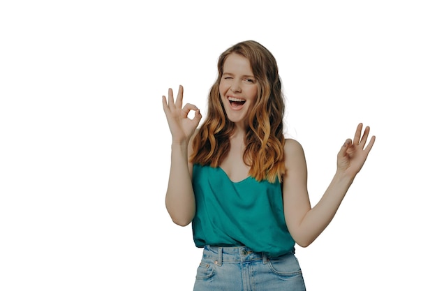 Charming funny girl shows OK sign with hands winking and looking at camera with big smile