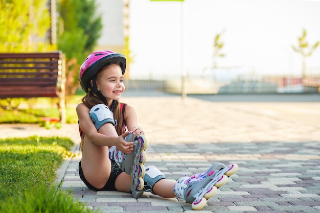 Charming girl of school age in short black shorts and a pink tshirt sitting on the floor and tries