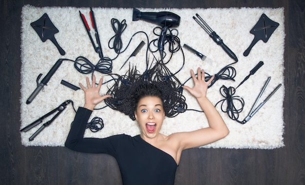 Photo the charming girl spread her hands to the side and screams. against the backdrop of the tools for creating a haircut