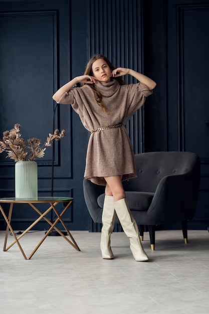 Charming girl with hair in posing in her mother's suede boots. Childhood, young actress, glamor. Full length shot