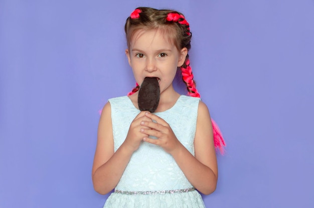 A charming girl with pink hair licks chocolate ice cream on a purple background Smiling and laughing A bright summer concept