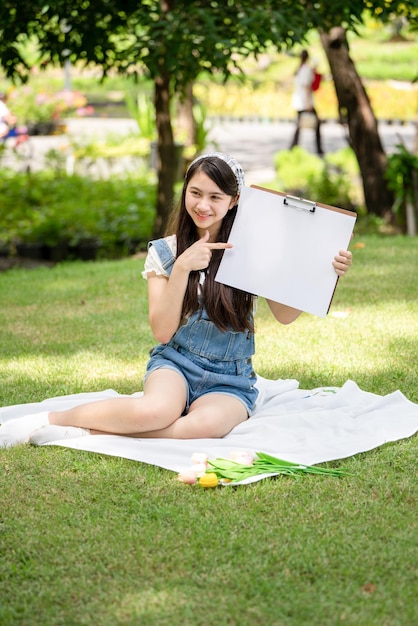 Charming Girl woman sitting on plaid at the park in sunny summer day and using watercolor