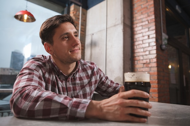 Charming handsome man enjoying drinking beer at local pub