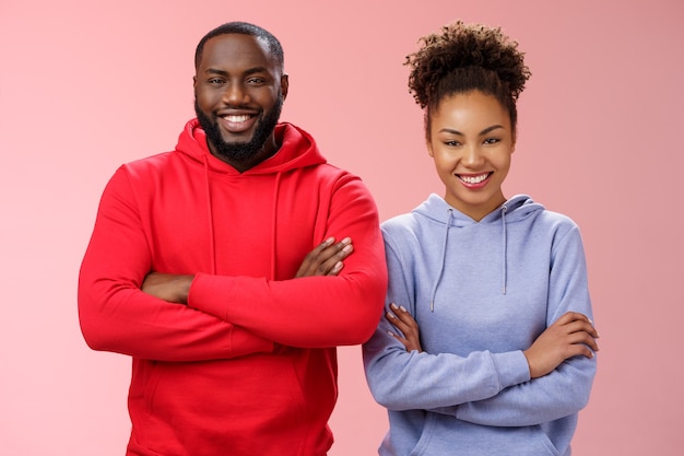 Charming happy professional team two african american man girl smiling broadly self-assured own abilities cross arms chest grinning friendly unbeatable working together, standing pink background