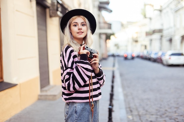 Charming hipster girl in hat with retro camera in city Travel concept lifestyle