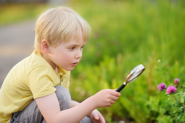 Charming kid exploring nature with magnifying glass