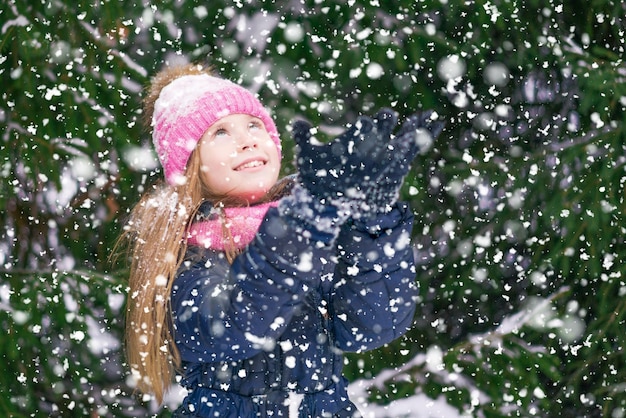 A charming kid puts palms up to catch snowflakes