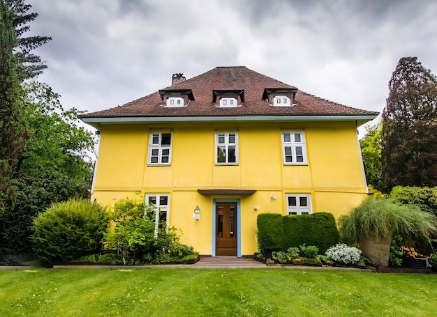 Charming Light Yellow house with wooden windows and a green grassy garden