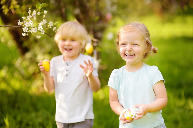 Charming little children hunting for painted eggs in spring park on Easter day.