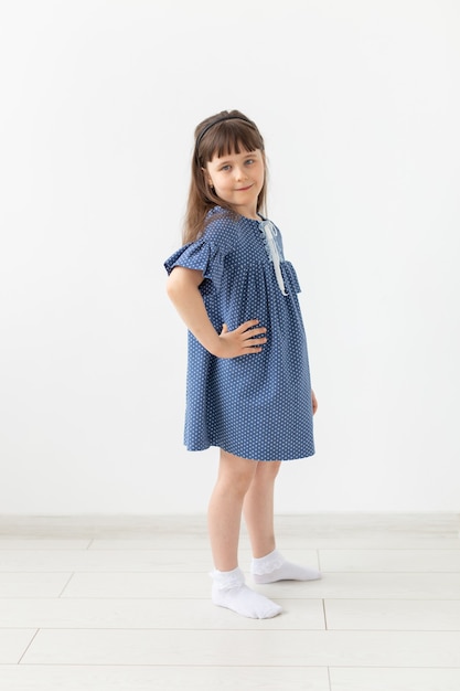 Charming little girl posing in blue polka dot dress on a white background. The concept of classic