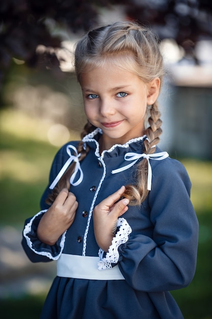 Charming little girl in a retro dress walking in the city on a sunny summer day. Little girl wear school uniform.