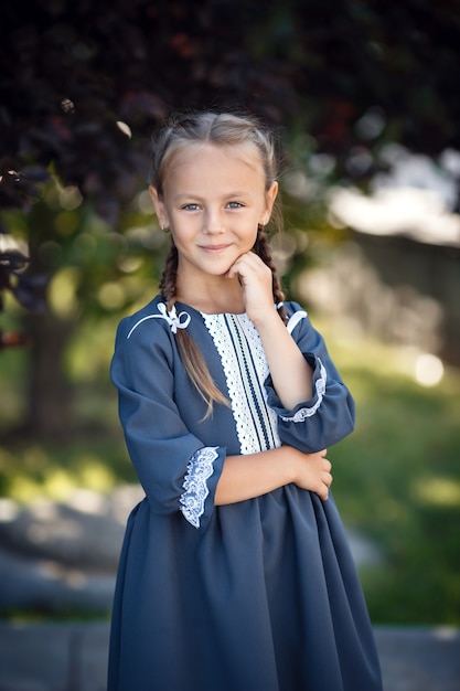 Charming little girl in a retro dress walking in the city on a sunny summer day. Little girl wear school uniform. 