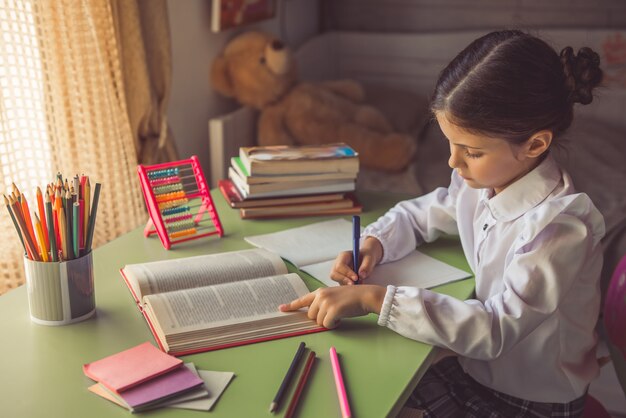 Charming little girl in school uniform is reading