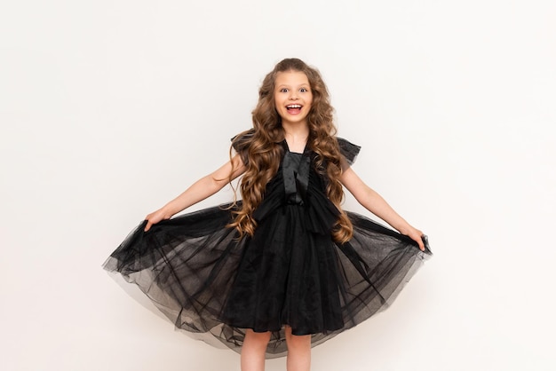 A charming little girl with curly hair and a fluffy dress on a white isolated background A beautiful princess on Black Friday