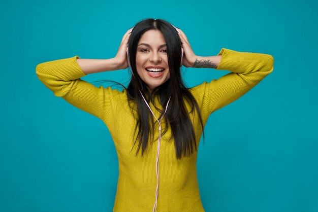 Charming model listening music with headphones, smiling.