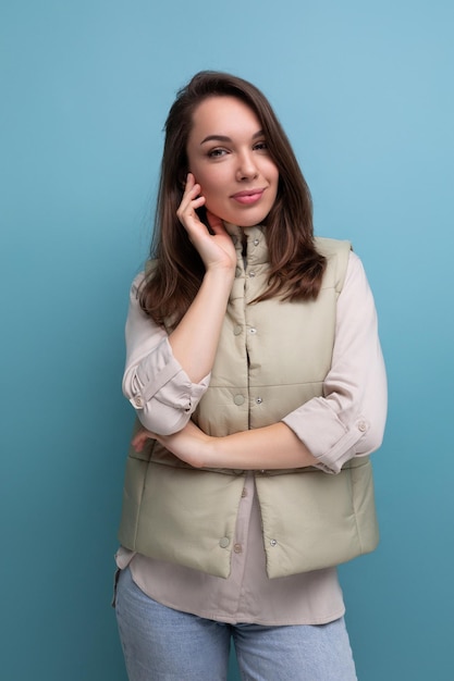 Charming positive brunette young lady in casual style on studio background