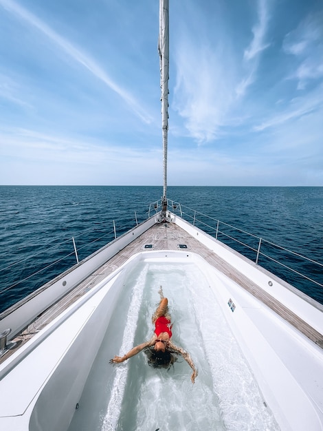 A charming slender woman swims in the pool located on the yacht