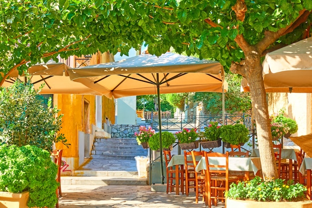 Charming street cafe with tables in a shade of the trees in Plaka district in Athens, Greece