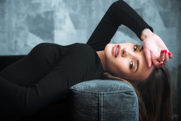 Charming woman in black dress on a couch