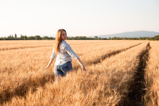 Charming woman enjoying moment walking in grain field