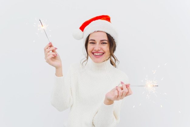 Charming woman posing with sparklers and laughing in the new year on a white background