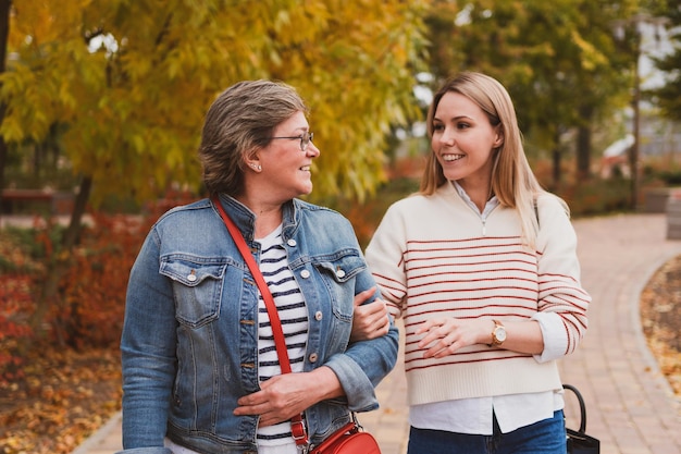 Charming women in casual style mom and daughter are walking in a beautiful autumn park