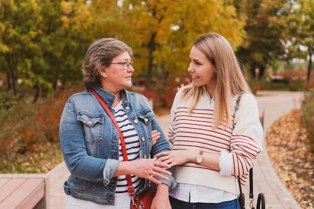 Charming women in casual style mom and daughter are walking in a beautiful autumn park