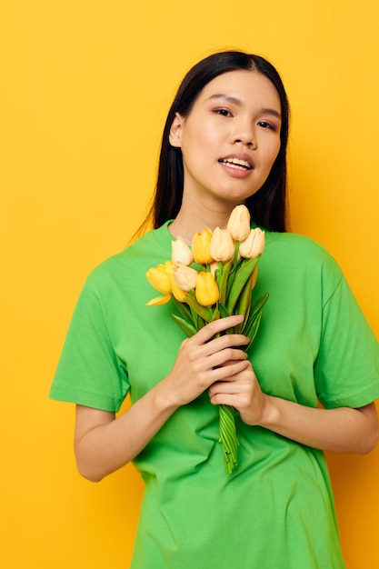 Charming young Asian woman green tshirt a bouquet of yellow flowers isolated background unaltered