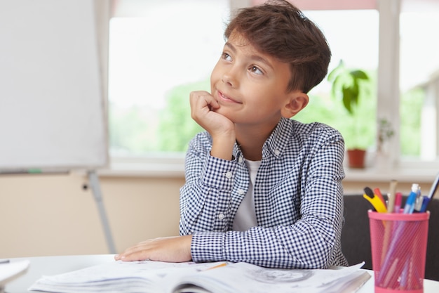 Charming young boy sketching in his textbook