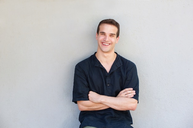 Charming young man smiling with arms crossed 