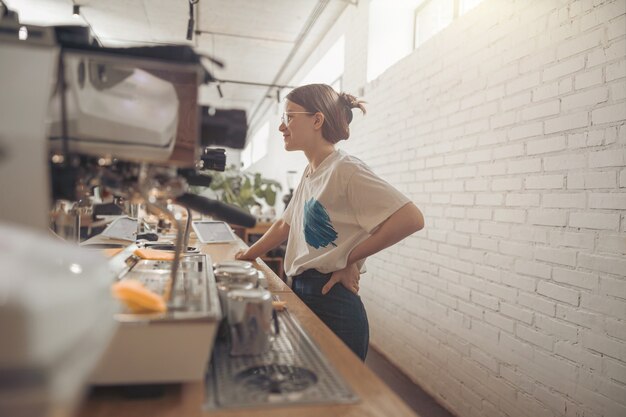 Charming young woman barista working in coffee shop