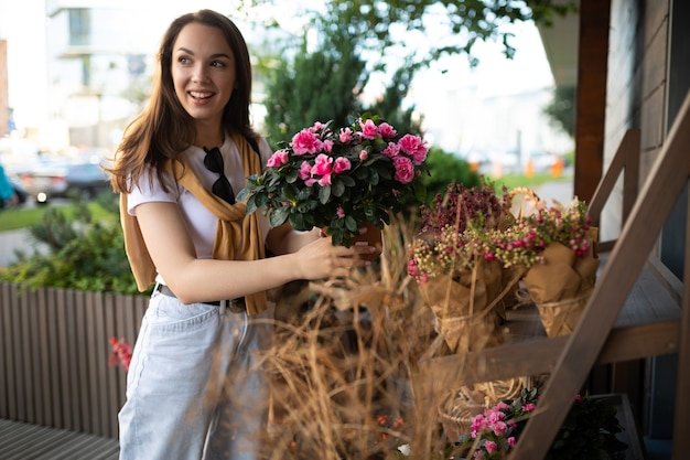 Charming young woman buying flowers at garden summer shop