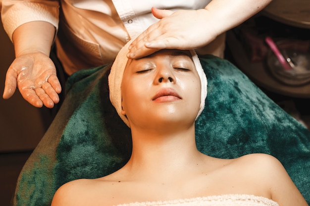 Charming young woman having facial massage with hyaluronic acid in a wellness spa center.