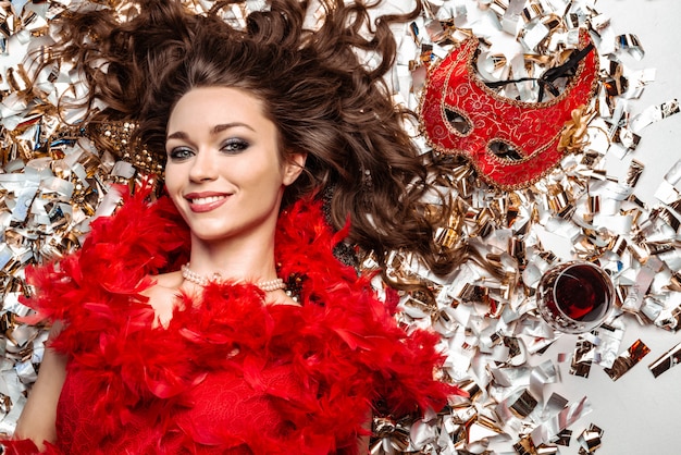 Charming young woman lying on the floor among golden tinsel