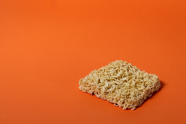 Cheap dry Chinese noodles without box, on orange background, side view, isolate