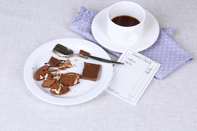 Check and cup of coffee on table closeup