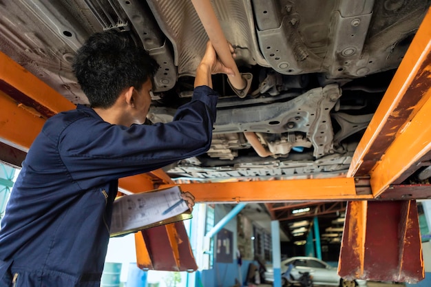 Check list. A man mechanic is fixing the engine on the car lift. by using car repair wrench tools in garage. service car concept.
