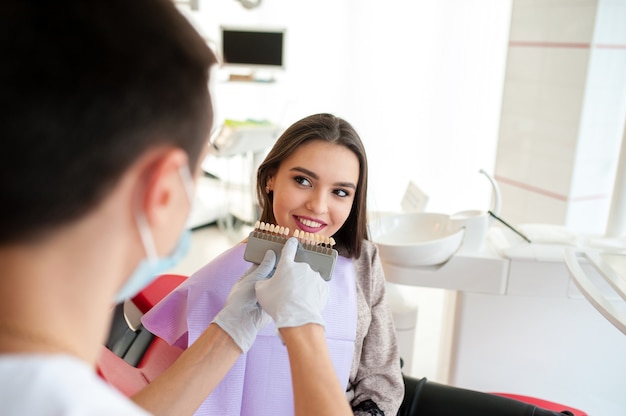 Check and select the color of the teeth for beautiful brunet girl.