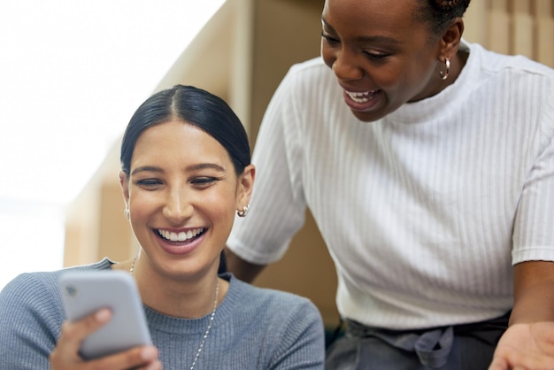 Check this out Cropped shot of two attractive young businesswomen looking at a cellphone together in the office