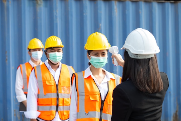 Checking the body temperature of workers by a thermometer