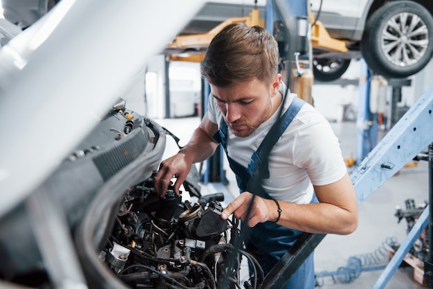 Checking if everything connected correctly. Employee in the blue colored uniform works in the automobile salon.