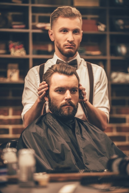 Checking symmetry. Hairdresser checking symmetry of haircut of his client at barbershop