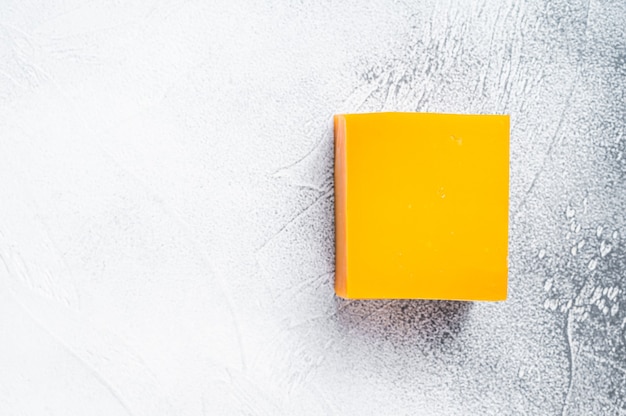 Cheddar Cheese block on a kitchen table. White background. Top view. Copy space.