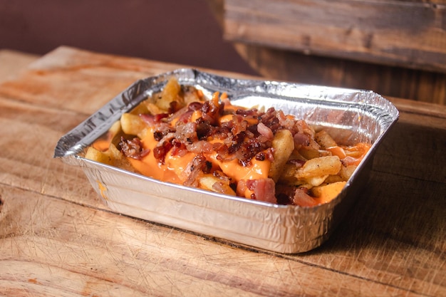 Cheddar cheese fries on a wooden table top